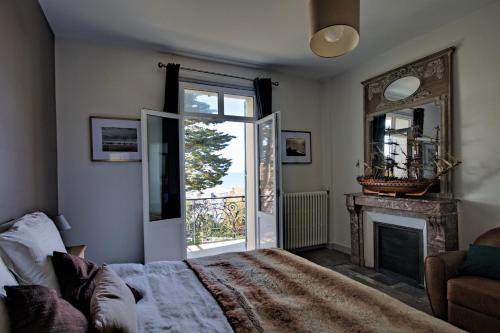 een slaapkamer met een bed, een open haard en een raam bij Villa Classée 4 étoiles Vue mer exceptionnelle in Trouville-sur-Mer