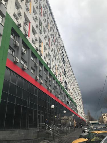 un grand bâtiment avec des voitures garées devant lui dans l'établissement Затишна Smart-Квартира, à Kiev