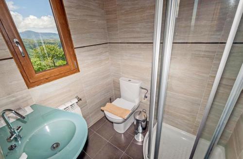 a bathroom with a toilet, sink and tub at La Trucha del Arco Iris in El Acebo de San Miguel