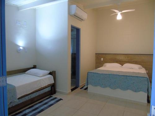 a bedroom with two beds and a ceiling fan at Pousada Sobre as Pedras in Itanhaém