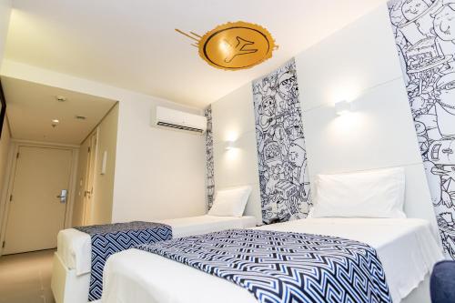 a bedroom with two beds and a clock on the wall at ibis Styles Rio de Janeiro Botafogo in Rio de Janeiro