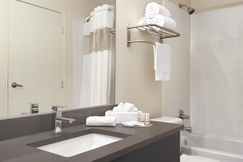 a bathroom with a sink and a toilet and a tub at Days Inn by Wyndham Kelowna in Kelowna