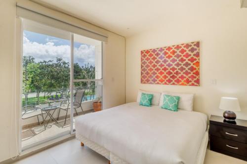 een slaapkamer met een bed en een groot raam bij Selvanova Coto 4B, Villa Flamingos 437F in Playa del Carmen