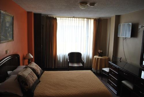 a hotel room with a bed and a window at Hotel Makroz in Latacunga