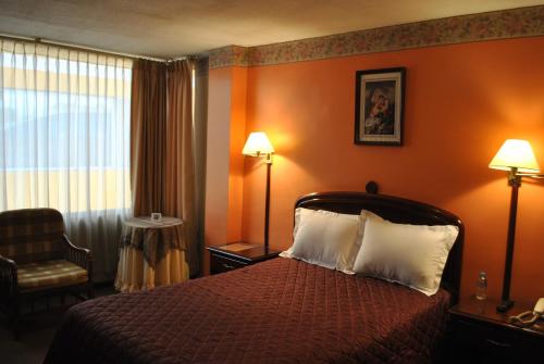 a hotel room with a bed and a chair at Hotel Makroz in Latacunga