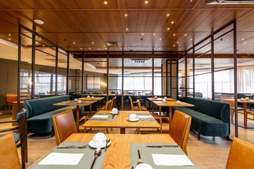 a restaurant with wooden tables and green chairs at Mercure Itajai Navegantes in Itajaí