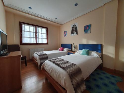 een hotelkamer met 2 bedden en een televisie bij Casa familiar con jardín “Arana Etxea” EBI01207 in Orduña