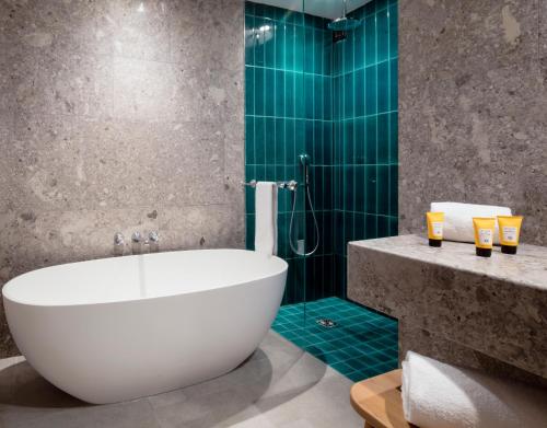 a bathroom with a tub and a shower with green tiles at Faloria Mountain Spa Resort in Cortina dʼAmpezzo