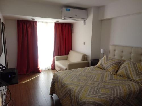 Un dormitorio con una cama y una silla y una ventana. en San Lorenzo 756, en Rosario