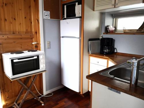 Elle comprend une petite cuisine équipée d'un réfrigérateur blanc et d'un évier. dans l'établissement Cosy cottage in a garden, à Ishøj