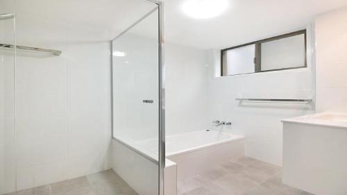 a white bathroom with a shower and a sink at Kingscliff Waters Apartment 5 in Kingscliff