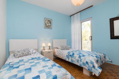 LastovoにあるHouse Andreaの青い壁の客室で、ベッド2台、窓が備わります。