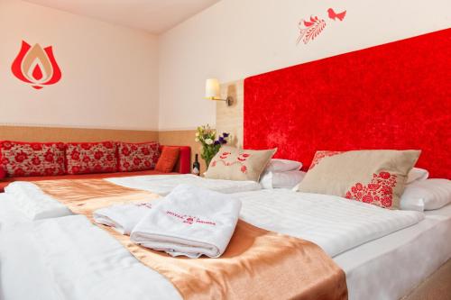 two beds in a room with a red wall at Hotel Piroska in Bük
