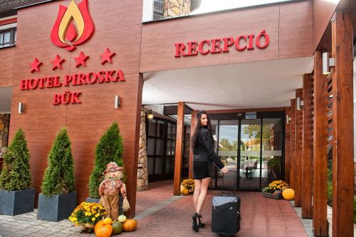 a woman walking in front of a hotel at Hotel Piroska in Bük