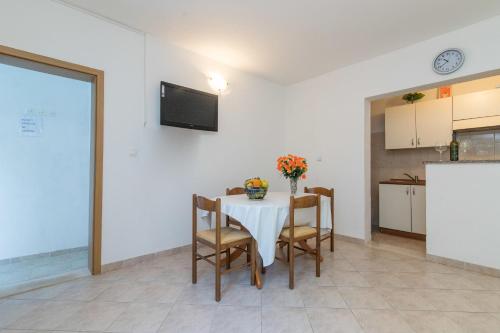 a dining room with a table with chairs and a kitchen at Apartment Matea in Ubli