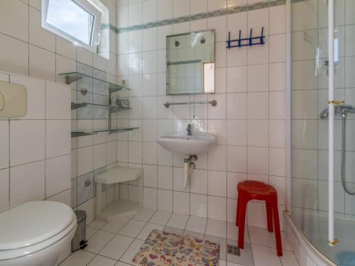 uma casa de banho com um WC, um lavatório e um banco vermelho em Apartments Sanela em Dramalj