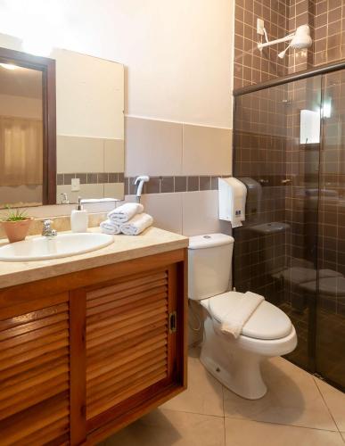 a bathroom with a toilet and a sink and a shower at Village Muta in Porto Seguro