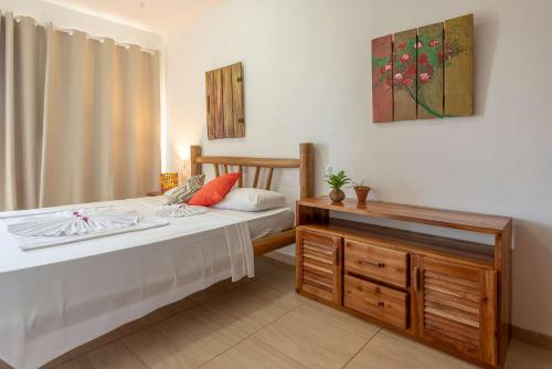 a bedroom with a bed and a dresser and a painting at Village Muta in Porto Seguro