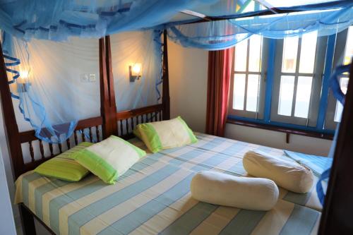 a bedroom with a bed with a blue canopy at Main Reef Guest House in Hikkaduwa