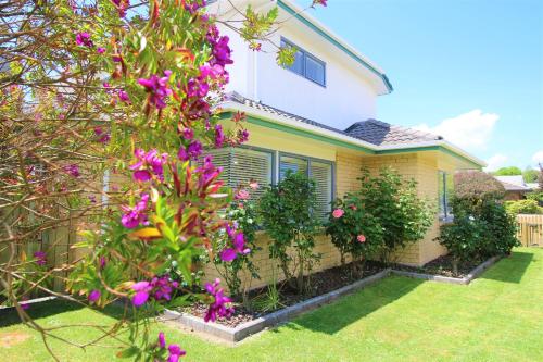a house with purple flowers in the yard at AristaAir- Central City Townhouse in Rotorua