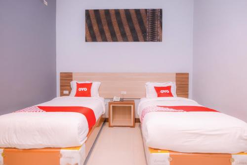 a room with two beds with red and white sheets at Super OYO Capital O 1630 Hotel Syariah Ring Road in Banda Aceh