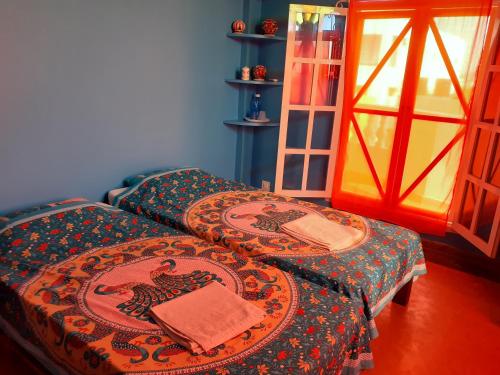 two twin beds in a room with a window at Holi-Wood Guesthouse in Pondicherry