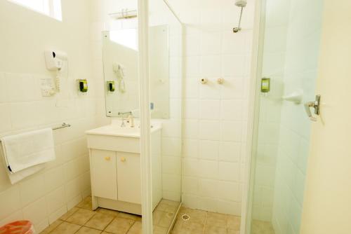 a white bathroom with a sink and a shower at Jacksons Motor Inn in Adelaide