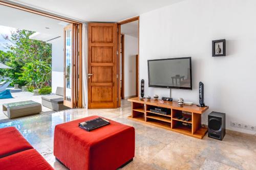 a living room with a television and a red stool at Umah CinCin in Canggu