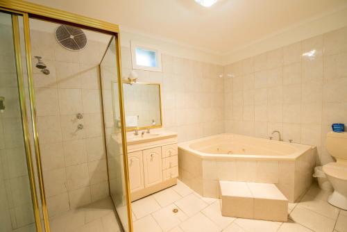a bathroom with a tub, toilet and shower at Jacksons Motor Inn in Adelaide