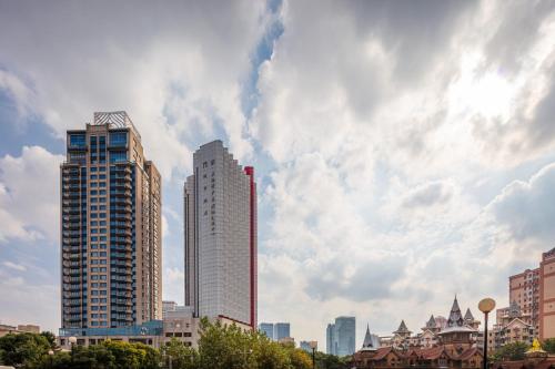 a city skyline with tall buildings and a cloudy sky at City Hotel Shanghai in Shanghai