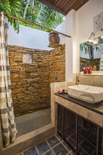 a bathroom with a sink and a stone wall at Eden Bungalows Fisherman's village in Bophut