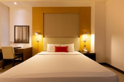 a bedroom with a large white bed with a red pillow at Ever Delightful Business Hotel in Chiayi City