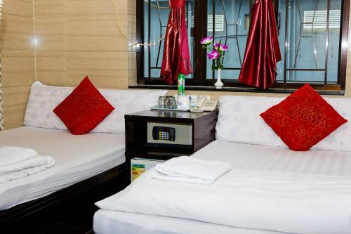 two beds in a room with red pillows on them at Asia inn (Block B) in Hong Kong
