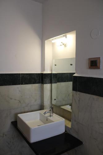 een badkamer met een witte wastafel en een spiegel bij Kaveri Hotel Bed & Breakfast in Mysore