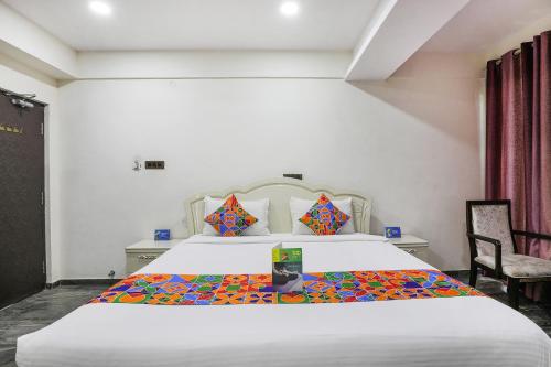 a bedroom with a large white bed and a chair at FabHotel Frazer Suites - Nr Bangalore Cantt Railway Station in Bengaluru