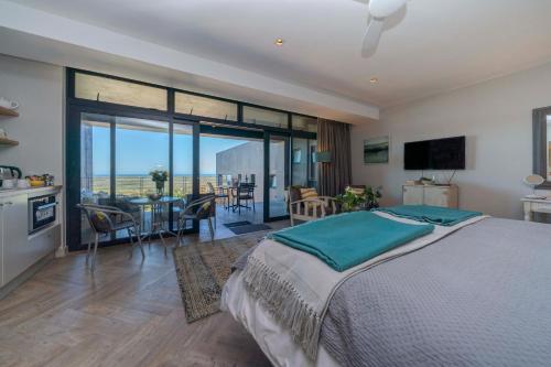 a bedroom with a large bed and a dining room at 365 Sunset Self Catering Apartments in Noordhoek