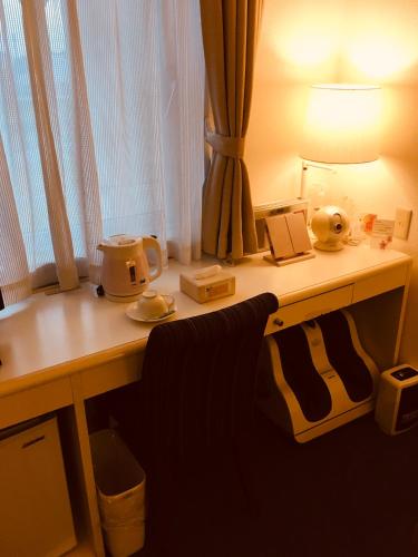 a desk with a lamp and a telephone on it at Business Inn Norte in Sapporo