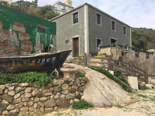 an old boat sitting in front of a building at Jin Sha Ting Hai Homestay I in Nangan