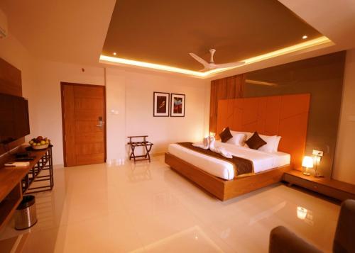 a bedroom with a large bed and a television at WithInn Hotel - Kannur Airport in Kannur