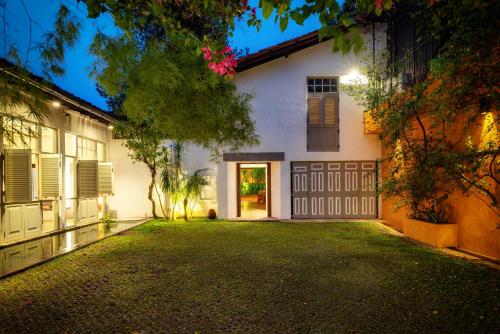 an exterior view of a white house with a driveway at De Saram House by Geoffrey Bawa in Colombo