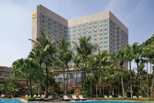 a large building with palm trees in front of it at Shangri-la Surabaya in Surabaya