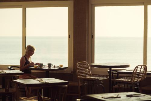 a woman sitting at a table in a restaurant at ICON Valparaiso - Adults Only in Cala Murada