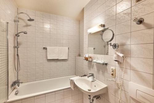 a bathroom with a tub and a sink and a shower at Landhotel Donaublick in Obernzell