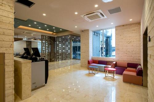 a lobby with a red couch and a table and chairs at Hotel Lantana Naha Matsuyama in Naha