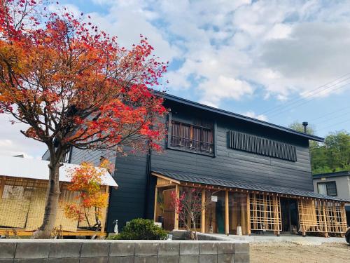 a black building with a tree in front of it at yuzaka - natural & sustainable inn - in Kazuno