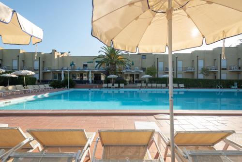 a swimming pool with chairs and an umbrella at Residence Le Acacie in Capoliveri