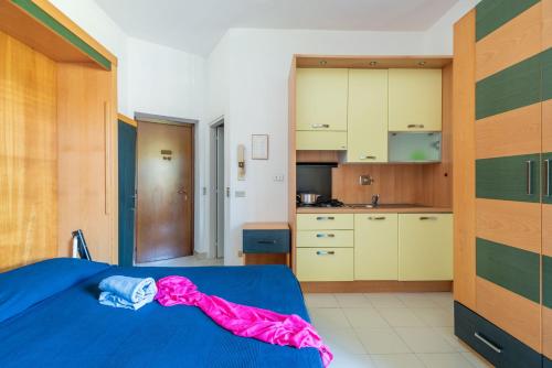 a bedroom with a blue bed and a kitchen at Residence Le Acacie in Capoliveri