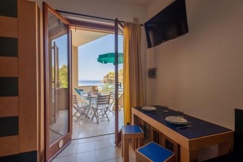 a kitchen with a table and a balcony with a view of the ocean at Residence Le Acacie in Capoliveri