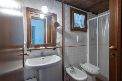 a bathroom with a sink and a toilet and a mirror at Residence Le Acacie in Capoliveri