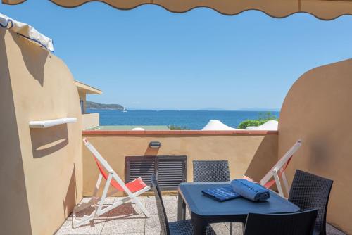 a table and chairs on a balcony with the ocean at Residence Le Acacie in Capoliveri